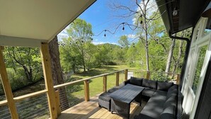 Una terrazza coperta con divano e tavolo, affacciata su un paesaggio naturale.