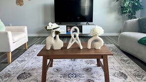 En moderne stue med et træ sofabord, et fladskærms-tv, en sofa og en potteplante.