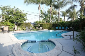A swimming pool with a hot tub, surrounded by palm trees and lounge chairs. - Destination #06 (Anaheim)