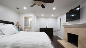 A bedroom with a bed, a ceiling fan, a TV, a fireplace, and a dresser. - Sweet 5 Bedroom, 4 Bath Pool Home 1/2 Mile Walk To Disney (Anaheim)