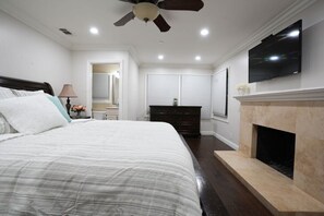 A bedroom with a bed, a ceiling fan, a TV, a fireplace, and a dresser. - Sweet 5 Bedroom, 4 Bath Pool Home 1/2 Mile Walk To Disney (Anaheim)