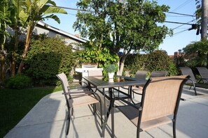 An outdoor patio with a table and chairs, surrounded by greenery and a building in the background. - Destination #06 (Anaheim)