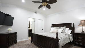 A bedroom with a bed, a ceiling fan, a TV, a dresser, and a lamp. - Sweet 5 Bedroom, 4 Bath Pool Home 1/2 Mile Walk To Disney (Anaheim)