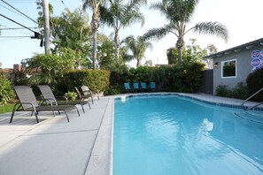 A swimming pool with lounge chairs, palm trees, and a building with a 'Diving' sign.