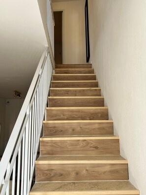 Staircase leads to a spacious interior with a white railing and natural wood finish.