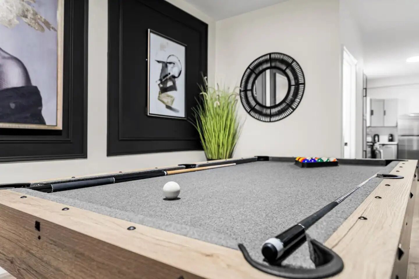 A pool table with a white cue ball, surrounded by pool cues and a set of colorful balls.