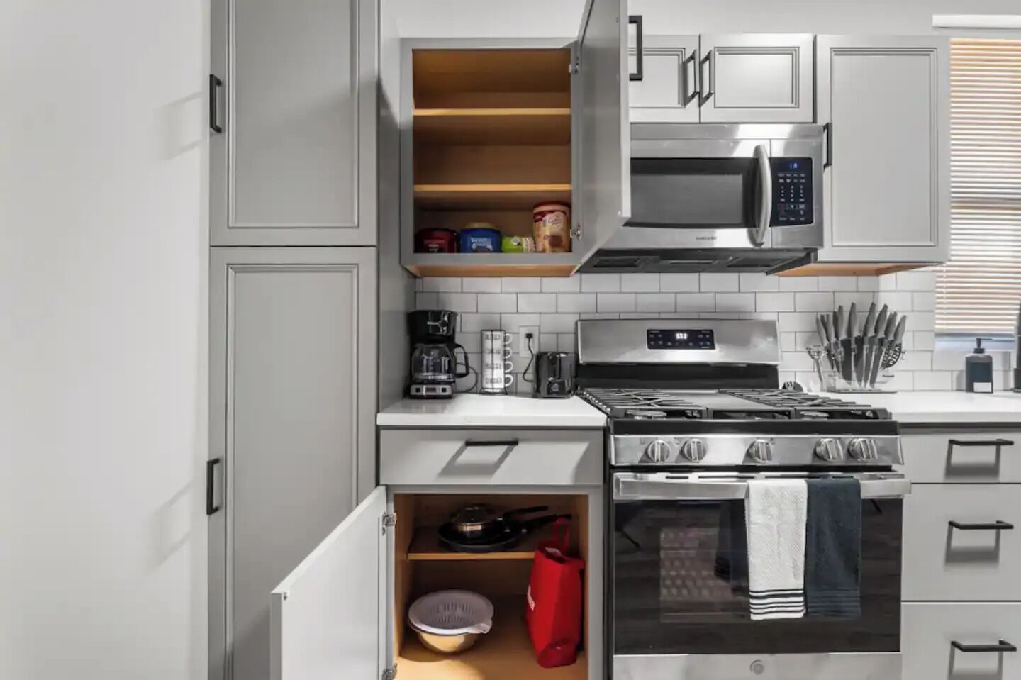 A modern kitchen with white cabinetry, a built-in microwave, a stove, and a coffee maker.