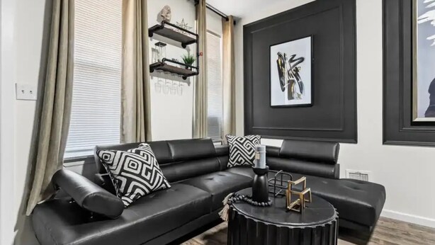 A modern living room with a black leather sofa, patterned cushions, a round coffee table, and a framed abstract painting on the wall. - Cozy & Stylish/Pool Table & Fun

 (Camden)