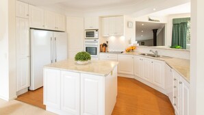 A modern kitchen with white cabinetry, a central island, a microwave, oven, and a sink. - Absolute lake frontage property located in the heart of beautiful Mallacoota.  (Mallacoota)