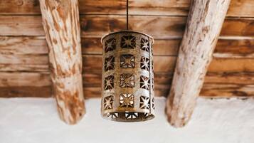 A hanging metal lantern with star-shaped cutouts, suspended from a wooden ceiling with exposed beams.