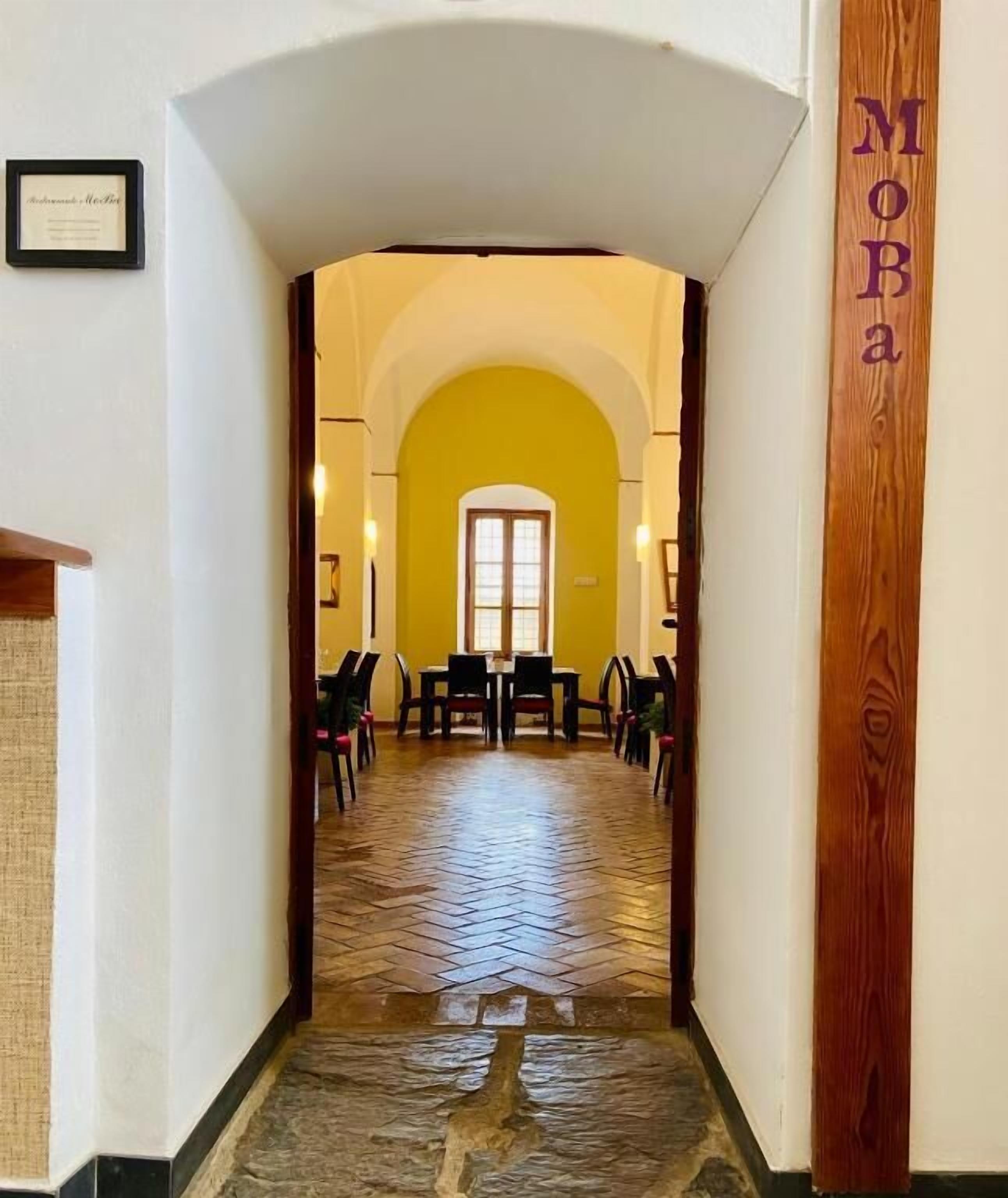 Un pasillo con pared amarilla, suelo de madera y una puerta al final.