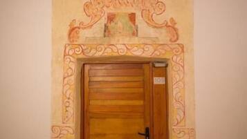 A wooden door with a decorative arch above it, featuring intricate patterns and a small plaque.