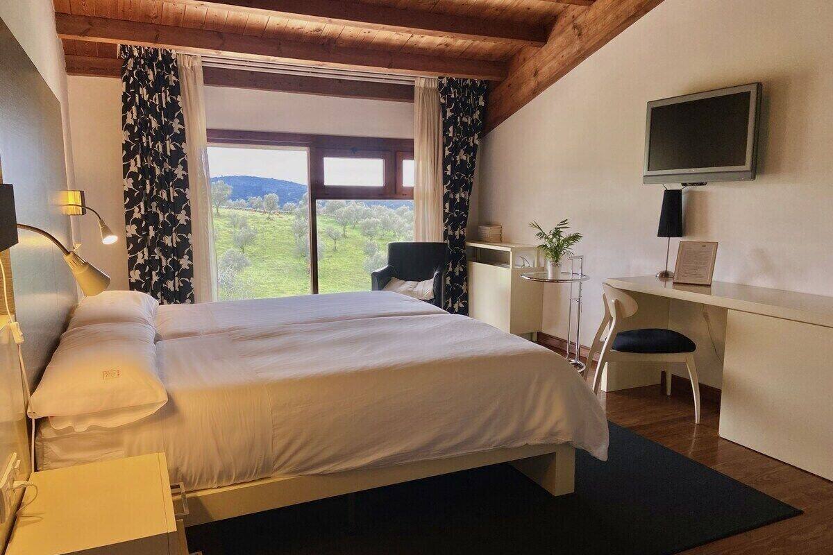 Un dormitorio con cama, escritorio, silla y televisor.
