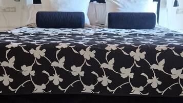 A bed with a black and white floral bedspread, a dark headboard, and two bedside lamps.