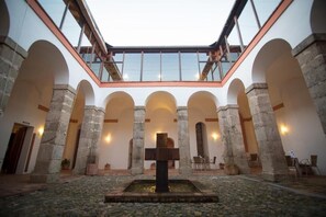 Un cortile con una fontana al centro, colonne in pietra e un soffitto in vetro.