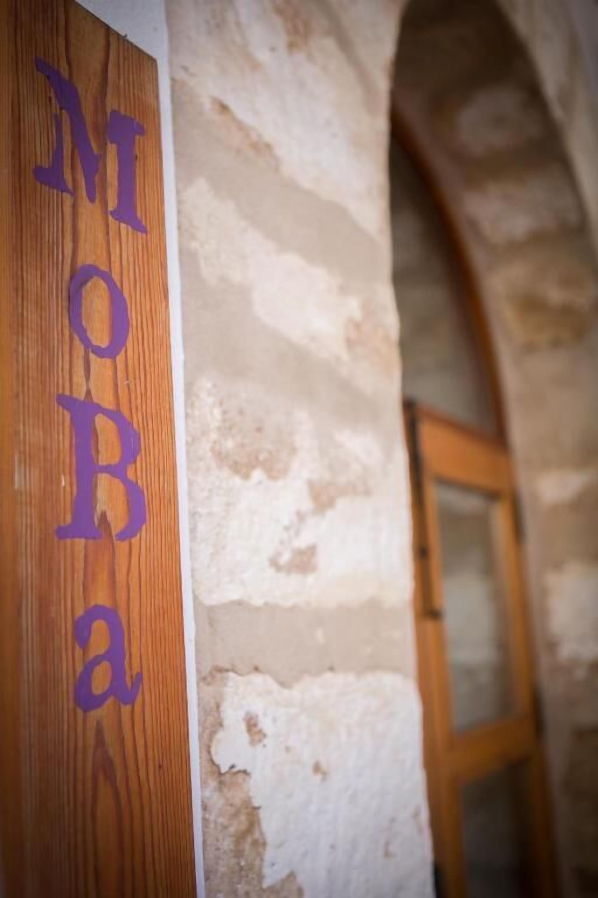A wooden sign with the letters "MOB" in purple.