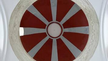 Elemento arquitectónico circular con un círculo blanco central rodeado de segmentos rojos y grises.
