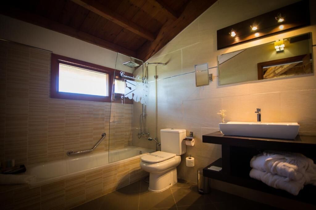 Un baño moderno con ducha de vidrio, inodoro blanco y lavamanos con espejo.