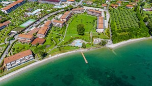 Eine Luftaufnahme eines Küstenresorts mit mehreren Gebäuden, einer großen zentralen Rasenfläche und einem Strand.