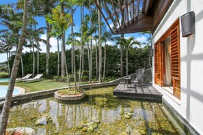 A pool area with lounge chairs, a wooden deck, and tall palm trees. - Casa de Campo Modern Villa for Rent All-inclusive Ocean View Villa With Chef Butler Maid (La Romana)