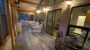 A spacious indoor area with a wooden floor, a dining table with chairs, and a sofa set.