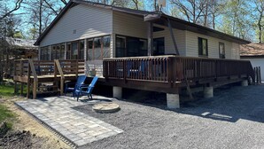 A single-story house with a covered porch, a gravel driveway, and a small garden area with a fire pit.