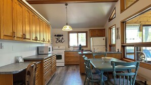 A kitchen with wooden cabinets, a central island, a dining table with chairs, and a refrigerator.