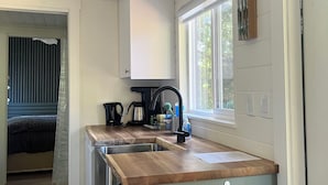 A compact kitchen with a wooden countertop, a sink, and a black kettle. - Malaspina Strait Tiny Home with easy access to town and trails for hiking/biking (Powell River)
