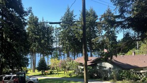 A residential area with a utility pole, a parked vehicle, and a house with a sloped roof. - Malaspina Strait Tiny Home with easy access to town and trails for hiking/biking (Powell River)