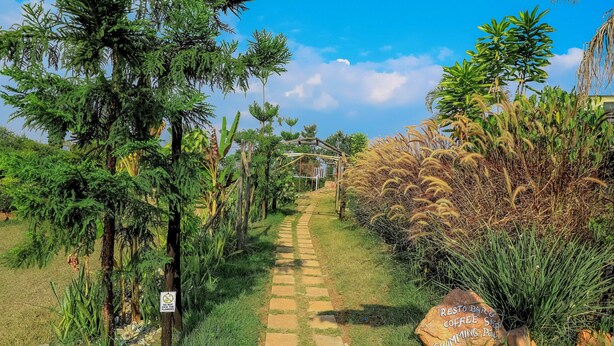 A pathway leading to a building with a sign indicating a rest area, coffee shop, and swimming pool. - Banana Eco Resort (Kiziguro)