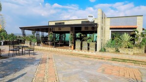 A building with a covered outdoor seating area, stone flooring, and a satellite dish. - Banana Eco Resort (Kiziguro)