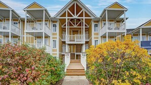 A multi-story hotel with a central atrium, balconies on each floor, and a well-maintained garden with autumn foliage.