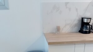 Eine Küche mit einer Holzarbeitsplatte, einer Kaffeemaschine und einem blauen Mülleimer.