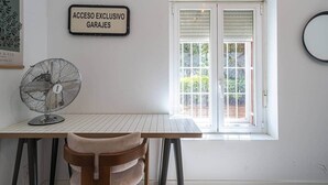 Ein Zimmer mit Tisch, Stühlen, einem Ventilator, einem Fenster mit Rollläden und einem Schild mit der Aufschrift 'ACCESO EXCLUSIVO GARAJES'.