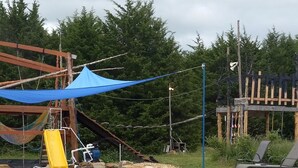 A playground with a slide, a small water feature, and a seating area with chairs.