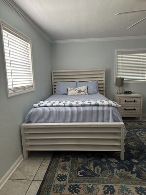 Une chambre à coucher avec un lit, des tables de chevet, une commode et un tapis à motifs.