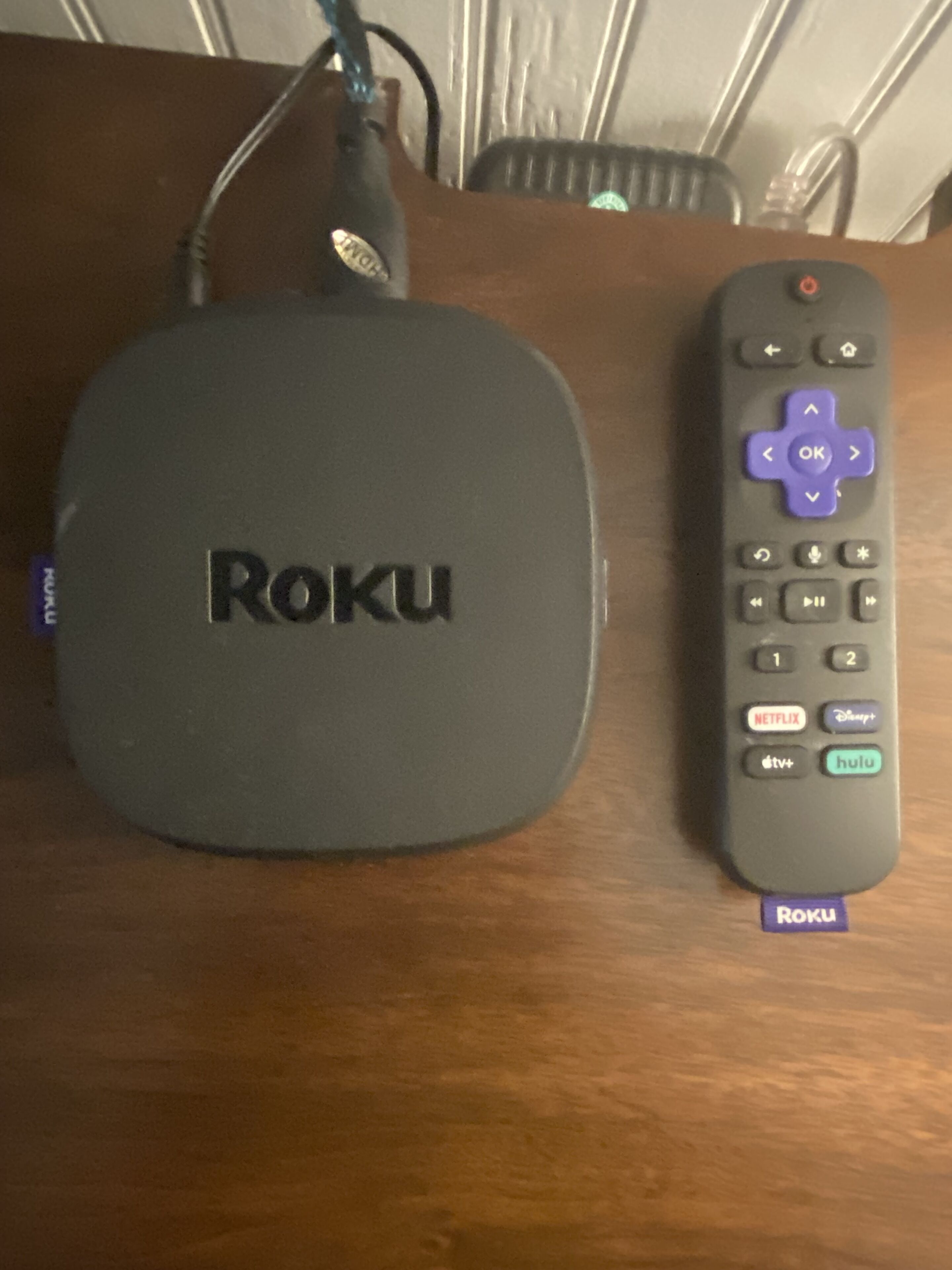 Un appareil de diffusion en continu Roku et sa télécommande, posés sur une table en bois.