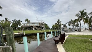 A wooden boardwalk leading to a waterfront area with a building in the background. - Waterfront Everglades basecamp with dock, trailer parking, and direct bay access (Ochopee)