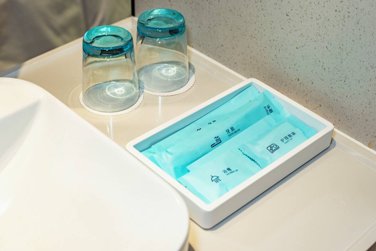 Un bagno con un lavandino bianco, un water e tre vasetti di vetro sul lavandino.