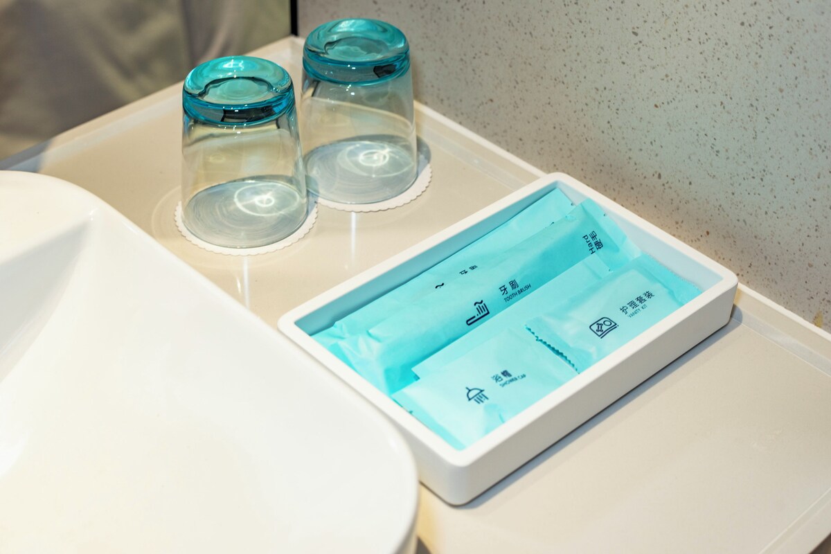 A bathroom with a white sink, a toilet, and three glass jars on the sink.