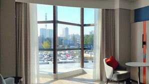 A modern hotel room with a large window offering a city view, a comfortable bed, a small table, and a chair. - Holiday Inn Express Yinchuan Lanxi Valley Plaza by IHG (Yinchuan)