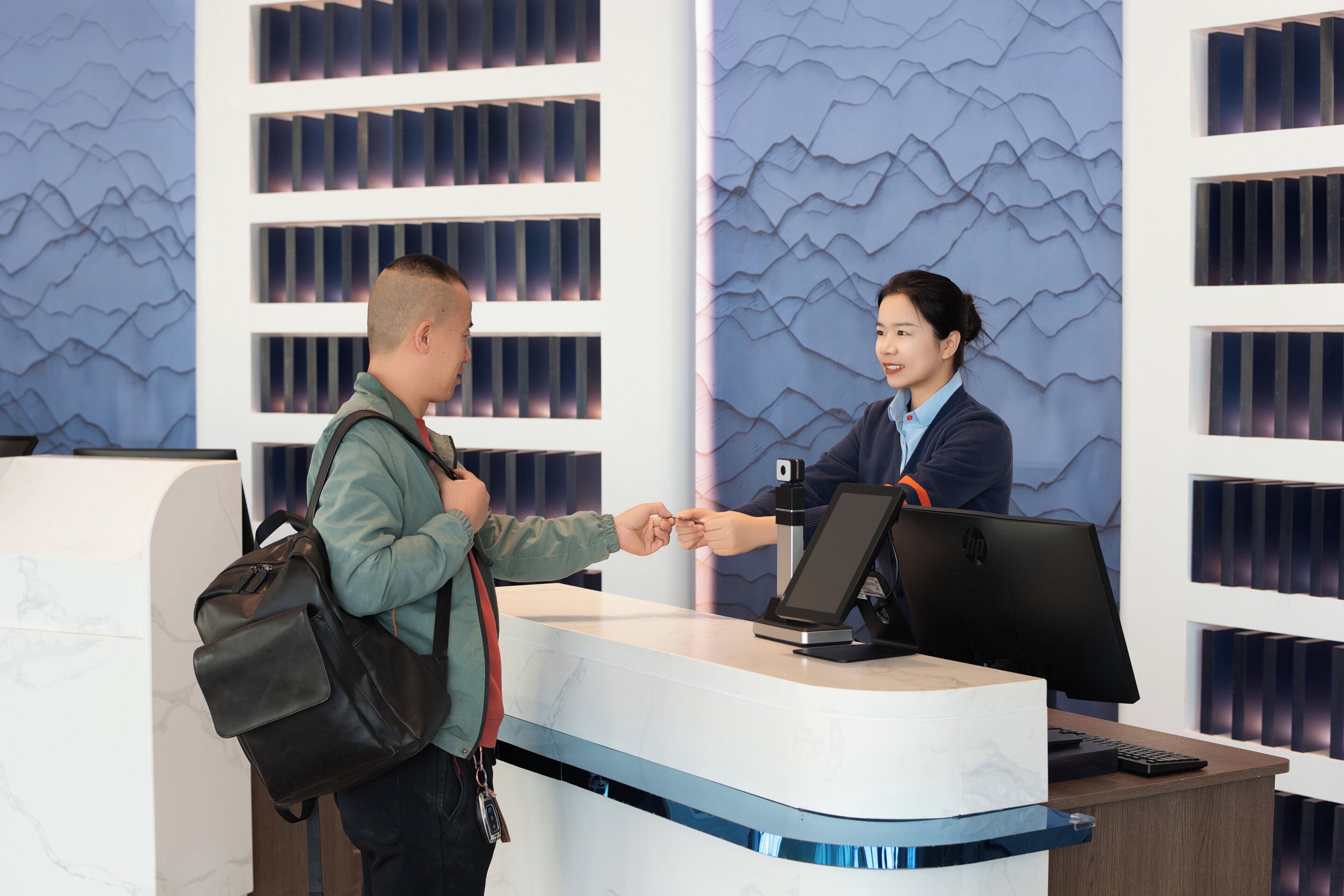 A reception desk with a modern design, a computer monitor, and a digital kiosk.