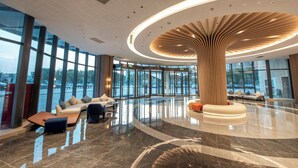 A spacious lobby with a central wooden column, seating areas, and large windows offering views of the outside. - Holiday Inn Express Yinchuan Lanxi Valley Plaza by IHG (Yinchuan)