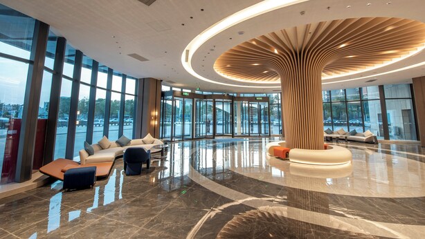 A spacious lobby with a central wooden column, seating areas, and large windows offering views of the outside. - Holiday Inn Express Yinchuan Lanxi Valley Plaza by IHG (Yinchuan)
