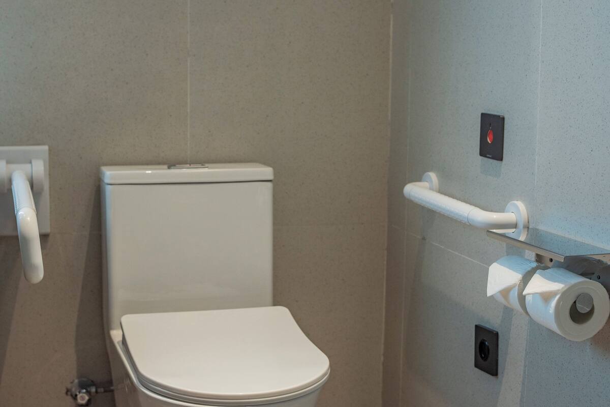Un bagno moderno con un water bianco, un asciugamani ad aria e un dispenser di carta.