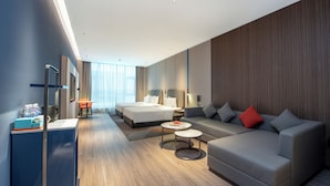 A modern hotel room with a bed, sofa, coffee table, and a desk with a computer. - Holiday Inn Express Yinchuan Lanxi Valley Plaza by IHG (Yinchuan)