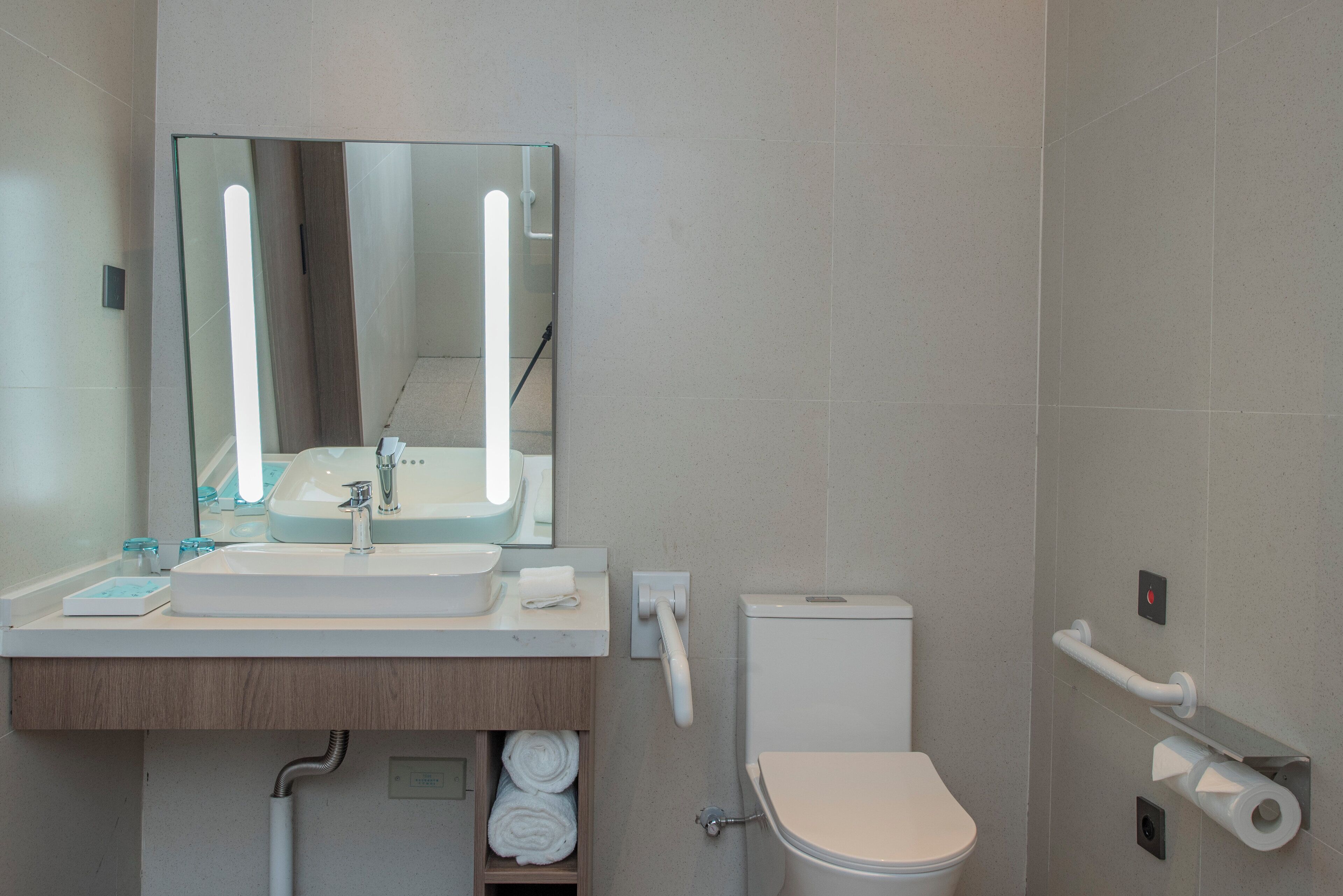 Ein modernes Badezimmer mit Waschbecken, Spiegel, Toilette und Handtuchhalter.