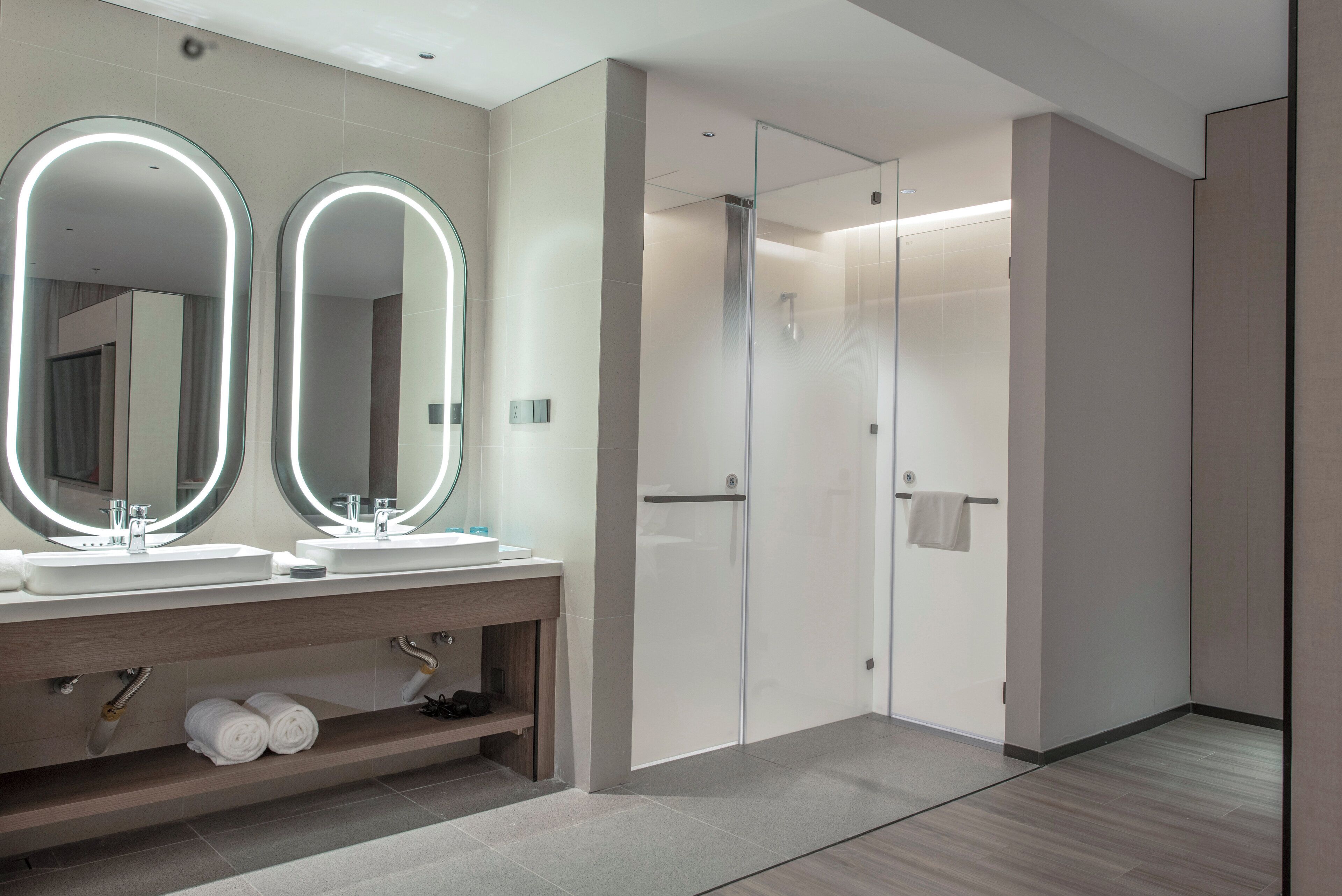 Ein modernes Badezimmer mit zwei Waschbecken, einem Waschtisch und einer begehbaren Dusche.