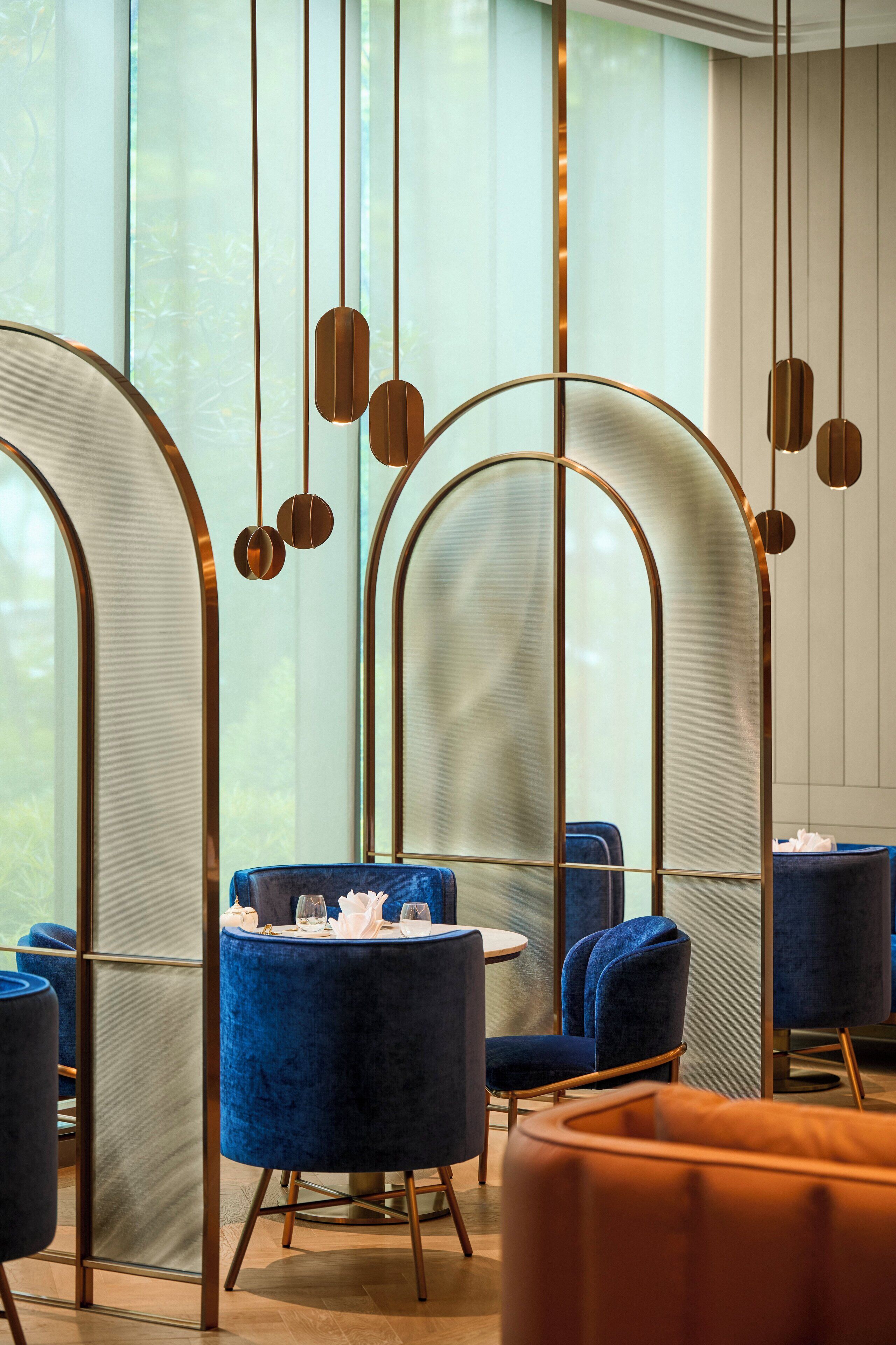 Un interior moderno con sillas de terciopelo azul, una mesa redonda y suelo de madera.