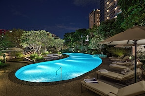 Una piscina al aire libre, sombrillas, sillones reclinables de piscina